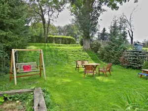 na zahradě je k dispozici venkovní posezení, ohniště, přenosný gril a houpací lavice