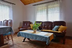 obývací místnost se sedací soupravou, krbovými kamny, jídelním a kuchyňským koutem