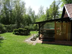 chata leží v zahradě, která je z větší části oplocená živým plotem