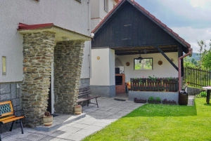 vchod do chalupy a altán s venkovním posezením a zahradním krbem