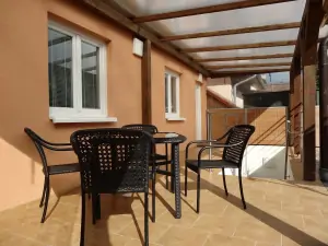 částečně zastřešená terasa se zahradním nábytkem a slunečníkem