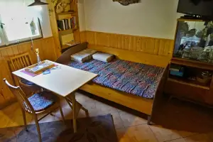 lůžko, stůl a 2 židle v obytném pokoji