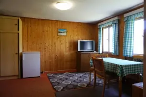 ložnice se čtyřlůžkem, stolem, židlemi a TV v podkroví