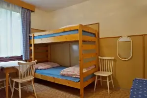 pokoj s rozkládacím gaučem, patrovou postelí, stolem a 4 židlemi