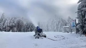 sněžné dělo v provozu na sjezdovce nad chatou