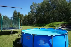 nadzemní zahradní bazén a za ním trampolína