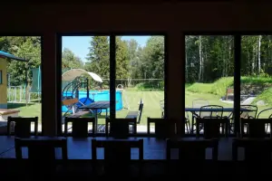 ze společenské místnosti je výhled na terasu s venkovním posezením i zahradu s bazénem a hřištěm