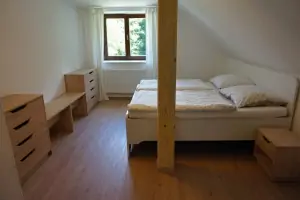 ložnice s dvojlůžkem a dětskou postýlkou v podkroví