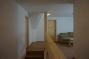 schody do podkroví vedou do otevřeného prostoru s gaučem a kuchyňským koutem