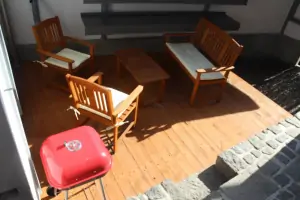 dřevěná veranda s nábytkem a přenosným grilem
