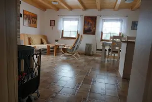 obytná místnost v přízemí s krbovými kamny, sedacím, jídelním a kuchyňským koutem