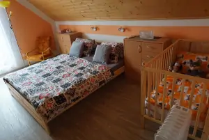 ložnice s dvojlůžkem, dětskou postýlkou a TV; společný balkón