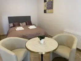 dvojlůžko, křesílka a stolek v pokoji apartmánu