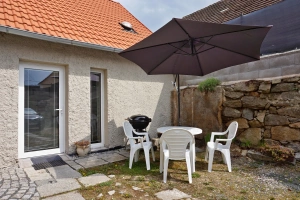 zahradní nábytek se slunečníkem a přenosný gril před vstupem do apartmánu