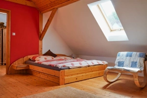 průchozí ložnice s dvojlůžkem, lůžkem a stolem s židlemi