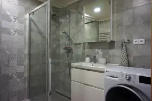 koupelna se sprchovým koutem, umyvadlem a pračkou