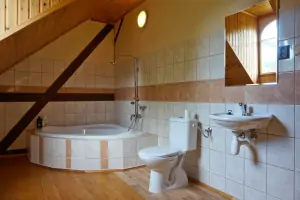 koupelna s vanou, umyvadlem a WC u průchozí ložnice s dvojlůžkem v podkroví