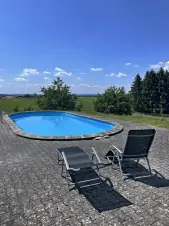 zapuštěný venkovní bazén s lehátky a výhledem do krajiny