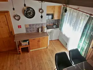 kuchyńský a jídelní kout v obytném pokoji; vstup na dlážděnou terasu s posezením