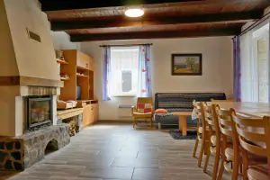 pravá část chalupy - obývací pokoj s krbem, sedacím a jídelním prostorem a kuchyňským koutem