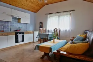 obývací místnost se sedací soupravou, krbovými kamny, jídelním a kuchyňským koutem