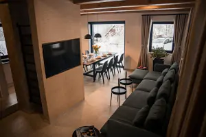 obývací místnost se sedací soupravou s TV, krbovými kamny, vstupem na terasu a kuchyňským a jídelním koutem