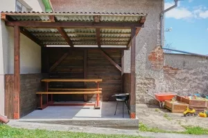 zastřešená pergola s posezením a přenosným grilem na dřevěné uhlí a pískoviště