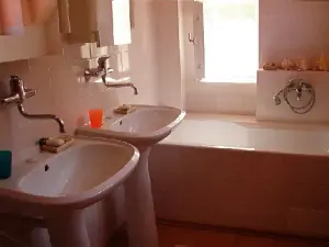 V koupelně jsou k dispozici 2 umyvadla, vana, sprchový kout a WC