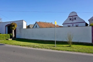 dvůr chalupy je od silnice chráněn vysokou zdí