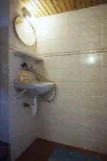 koupelna s ruční sprchou, umyvadlem a WC (od obytné kuchyně je oddělena závěsem)
