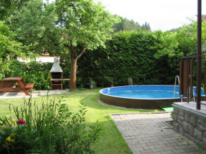 Vedle bazénu se nachází venkovní posezení a zahradní krb