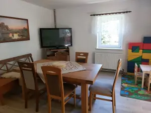 stůl, židle, TV a dětský koutek v obytné kuchyni