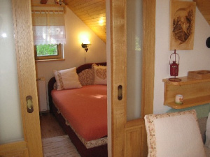 Ložnice s manželkou postelí je oddělena od obytného pokoje zasunovacími dveřmi