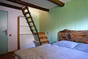 z ložnice s dvojlůžkem vedou příkré schody do otevřené podkrovní ložnice s dvojlůžkem