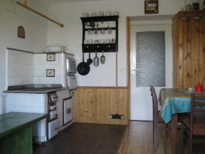 Kuchyně ve sníženém přízemí s kachlovými kamny a jídelním koutem